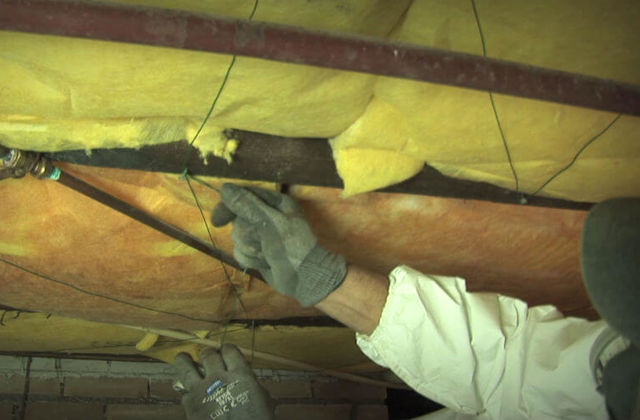 Vloerisolatie. Een medewerker van het isolatiebedrijf bevestigt het isolatiemateriaal.
