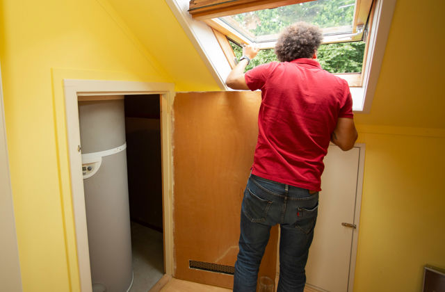 Man kijkt uit schuin dakraam. In kast ernaast staat de binnenunit van een warmtepomp.