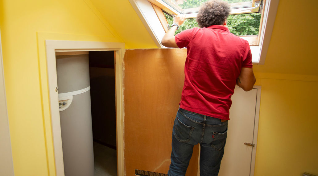 Man kijkt uit schuin dakraam. In kast ernaast staat de binnenunit van een warmtepomp.