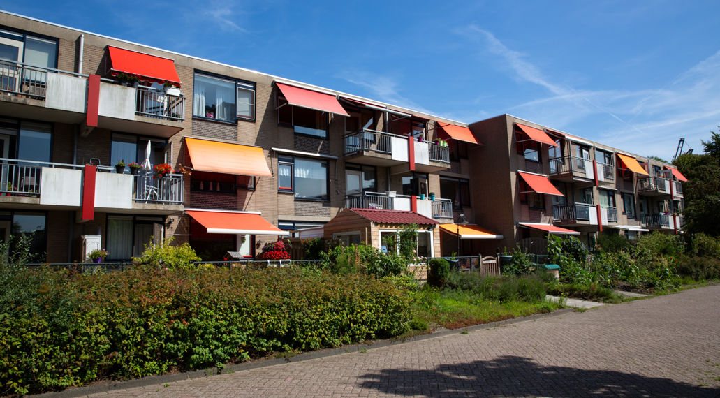 Appartementgebouw met zonneschermen als zonwering, om de warmte buiten te houden.