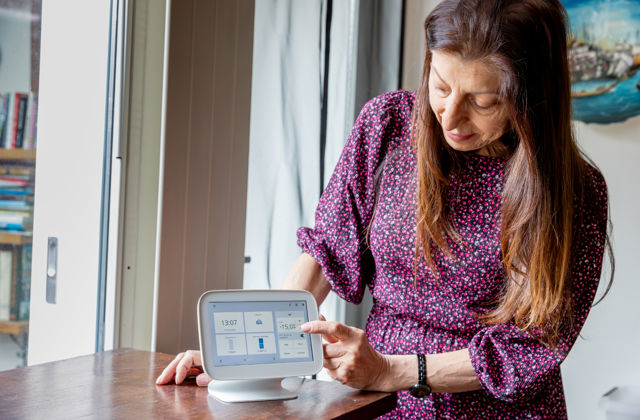 Een vrouw zet haar thermostaat lager om energie te besparen.