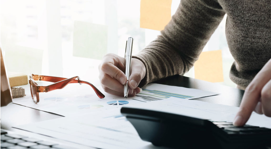 Hand met pen en rekenmachine. Berekeningen maken