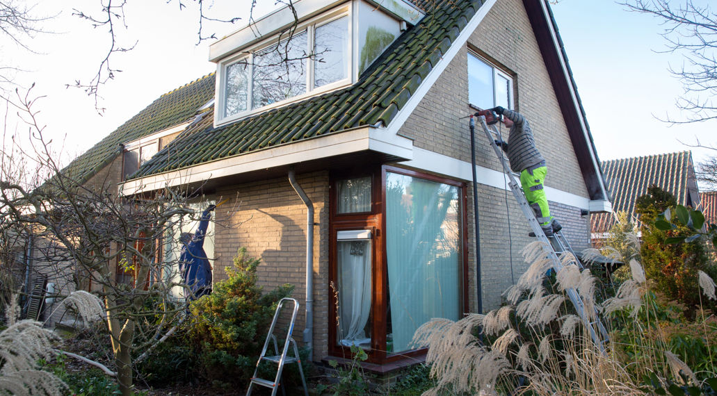Twee medewerkers van het isolatiebedrijf brengen spouwmuurisolatie aan.