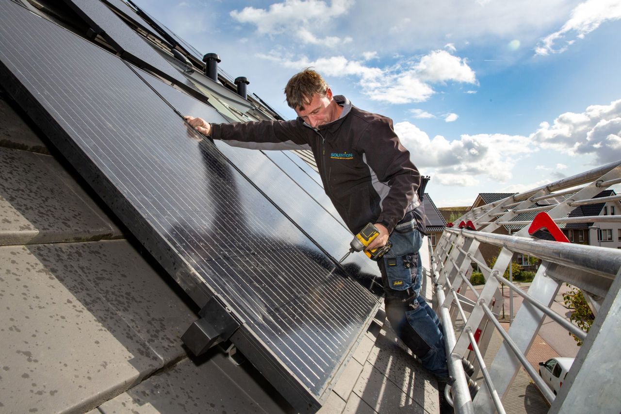 Een installateur installeert zonnepanelen op een dak.