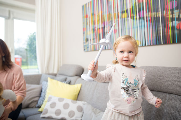 Meisje met speelgoed windmolentje op de bank. Bespaar energie door je huis te verduurzamen.
