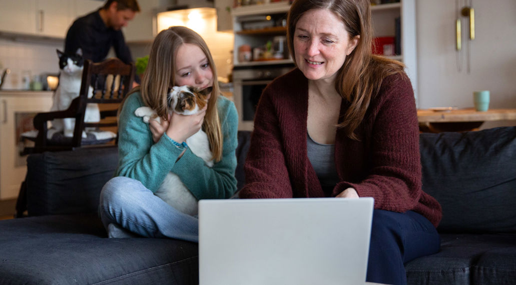 Een vrouw laat haar tienerdochter iets zien op haar laptop.