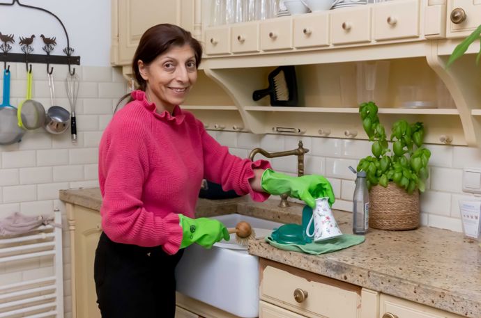 Een vrouw doet de handafwas in een teiltje.