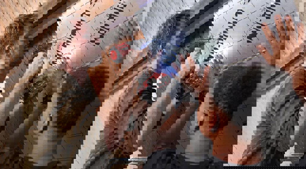 Twee mensen isoleren het dak met isolatieschuimplaten.