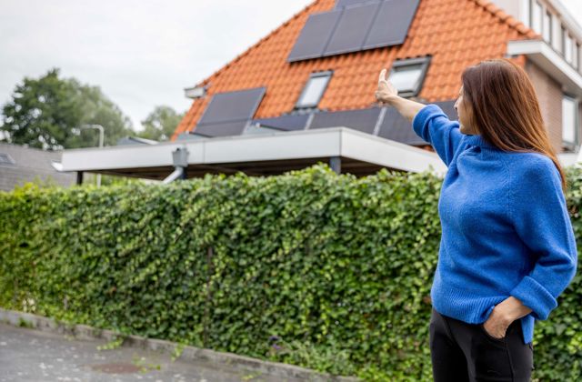 Iemand wijst naar zonnepanelen op een dak.