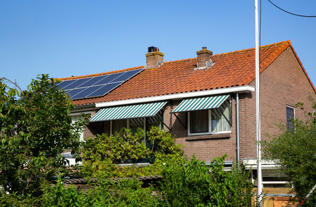 Huis met zonneschermen en veel groen om het huis.