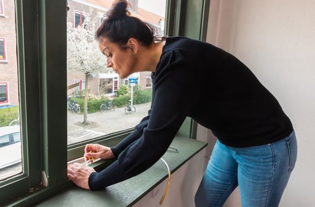 Een vrouw plaatst tochtband.