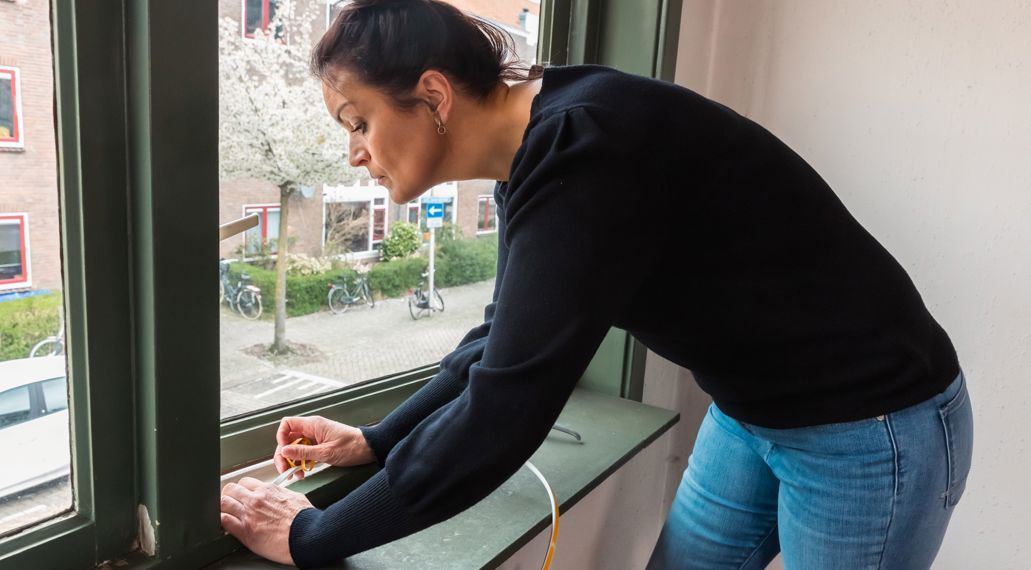 Een vrouw plaatst tochtband.