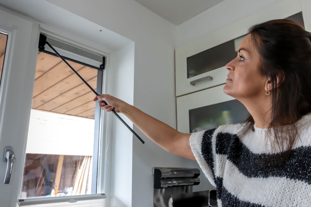 Vrouw zet ventilatierooster in raam open