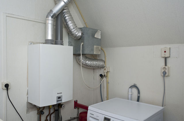 Ventilatiebox hangt naast de cv-ketel op zolder.