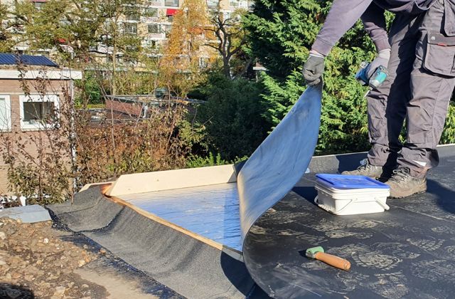 Isolatiemateriaal op een plat dak. De dakdekker laat het materiaal zien.