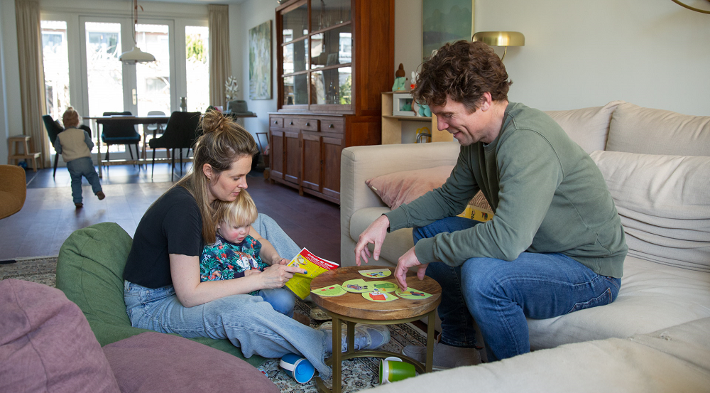 Een jong gezin speelt een spelletje in hun goed geïsoleerde woning.